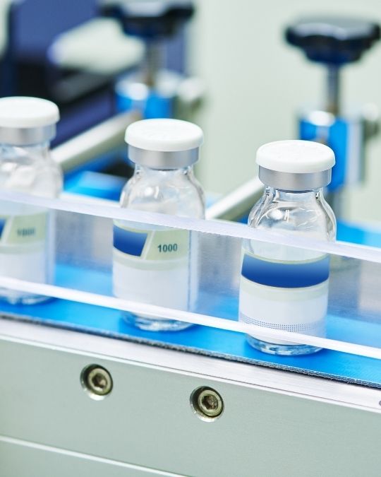 Flacons pharmaceutiques sur convoyeur de ligne de conditionnement en laboratoire