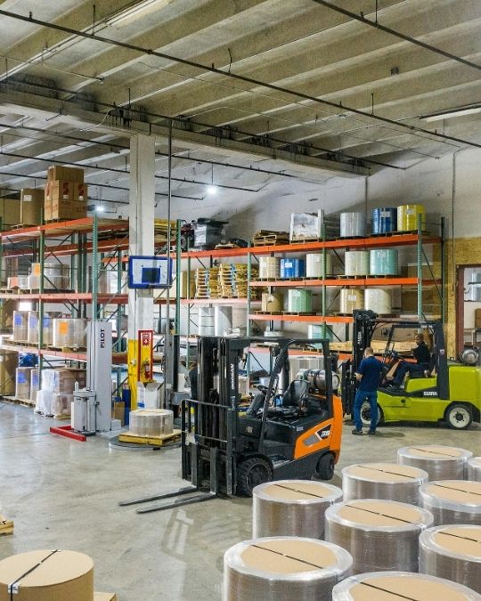 Entrepôt logistique industriel avec chariots élévateurs et rayonnages de stockage en activité